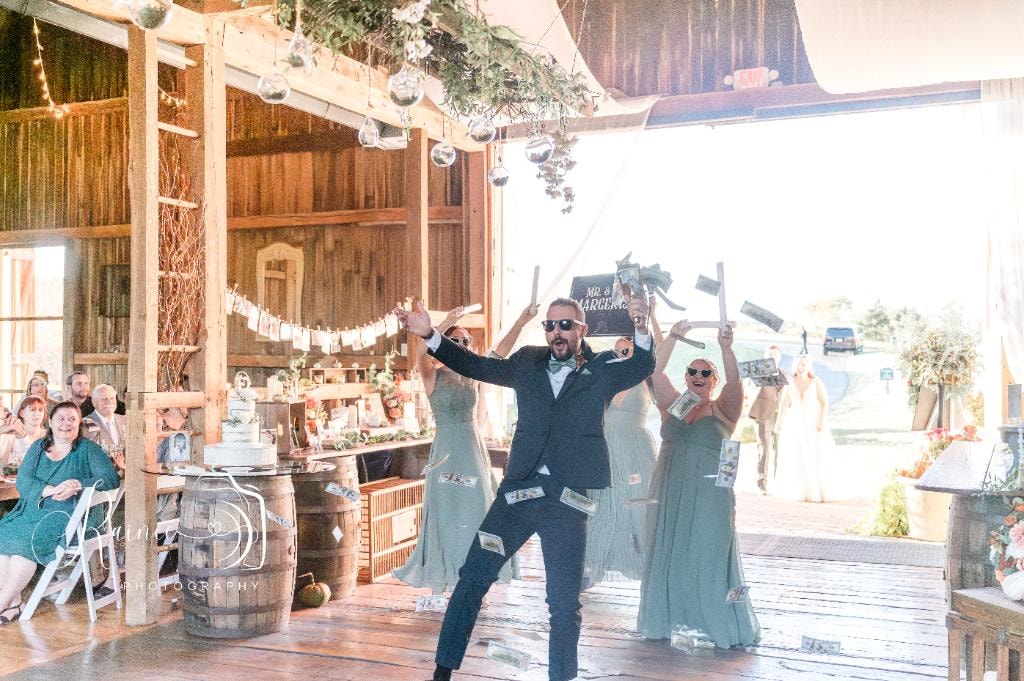 Groom making grand entrance at rustic barn wedding reception